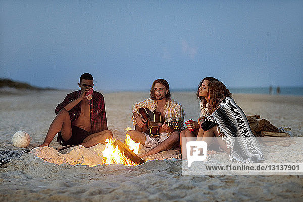 Freunde sitzen am Lagerfeuer am Strand