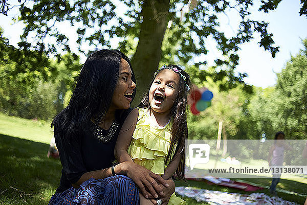 Glückliche Mutter spricht mit Tochter während Geburtstagsfeier im Park