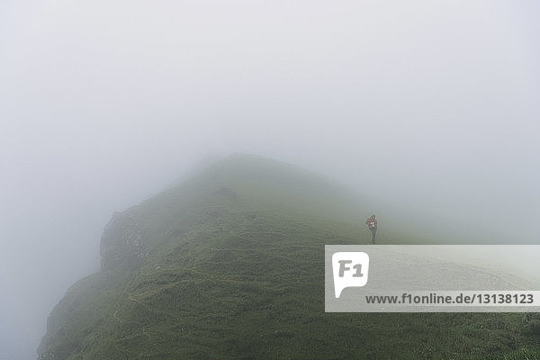 Hochwinkelaufnahme eines Wanderers  der bei nebligem Wetter auf einem Hügel steht