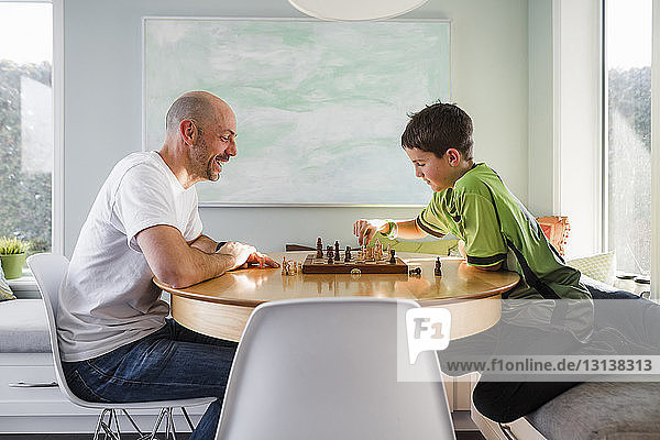 Seitenansicht von Vater und Sohn beim Schachspiel zu Hause