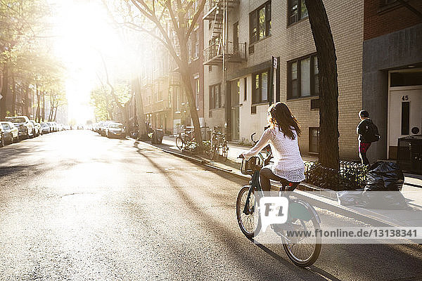 Rear view of young woman riding bicycle on street