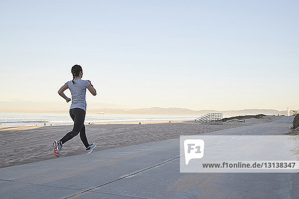 Woman jogging against sea and clear sky