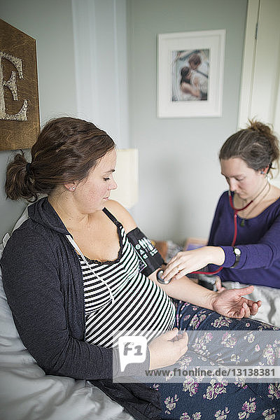 Midwife examining pregnant woman at home