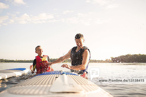 Vater und Sohn genießen am See gegen den Himmel an einem sonnigen Tag