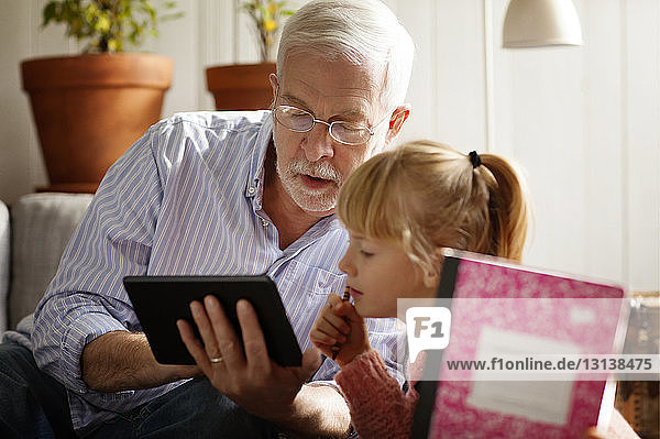Großvater zeigt Enkelin Tablet-Computer beim Lernen zu Hause