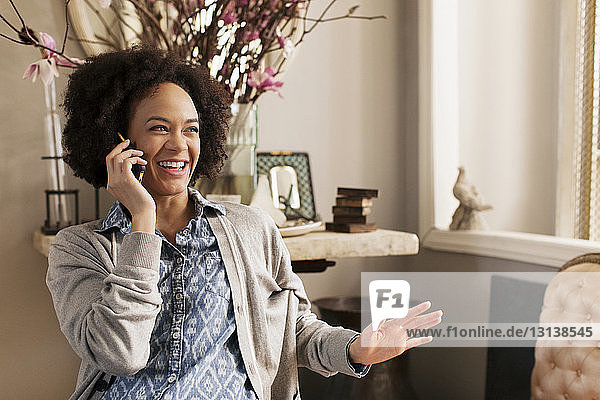Glückliche Frau spricht zu Hause am Smartphone