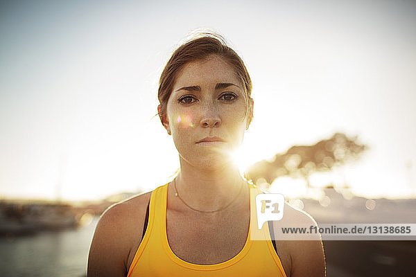 Porträt einer selbstbewussten Sportlerin vor klarem Himmel bei Sonnenuntergang