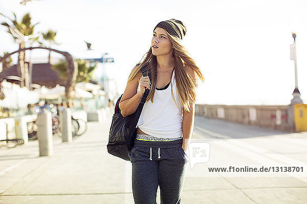 Fashionable young woman walking on street against clear sky