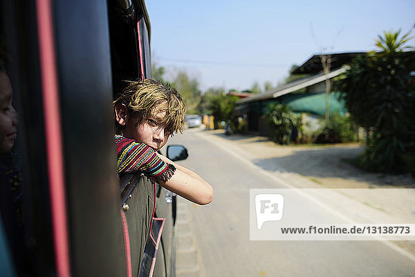 Portrait of boy leaning on window while traveling with mother in vehicle