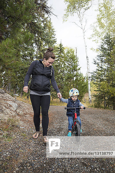 Son holding mother's hand while riding bicycle