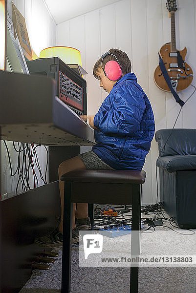 Seitenansicht eines Jungen  der beim Abspielen von Audiogeräten zu Hause einen Gehörschutz trägt