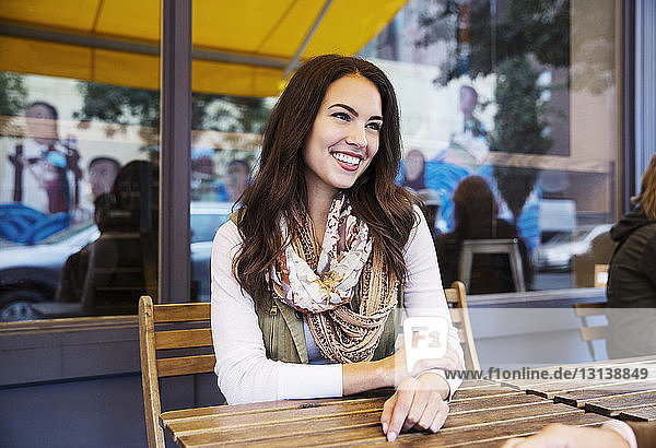 Happy woman sitting at sidewalk cafe
