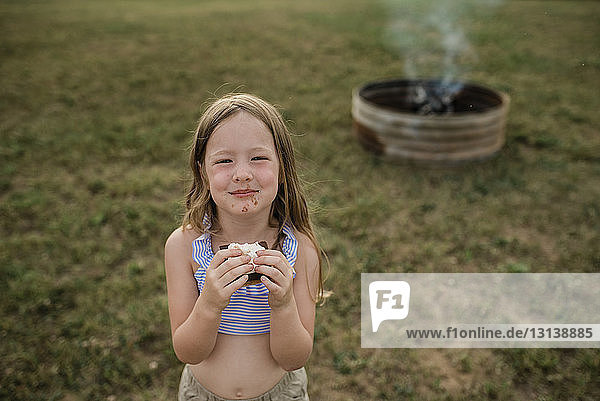 Portrait of smiling girl having smore at backyard