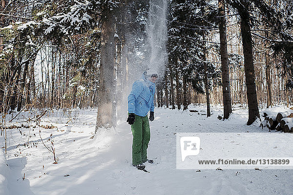 Man standing on snow covered field in forest