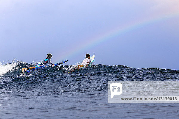 Freunde surfen auf dem Meer gegen den Himmel