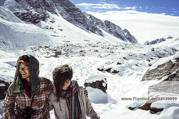 Happy friends standing at snowcapped mountain