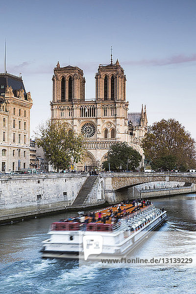 Schiffsreisende auf der Seine bei Notre Dame de Paris gegen den Himmel