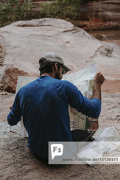 Rear view of man reading map while sitting at Grand Canyon National Park