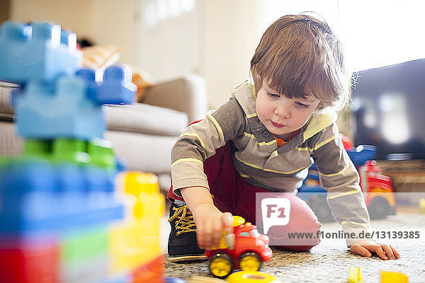 Niedrigwinkelansicht eines Jungen  der zu Hause mit einem Spielzeuglastwagen spielt
