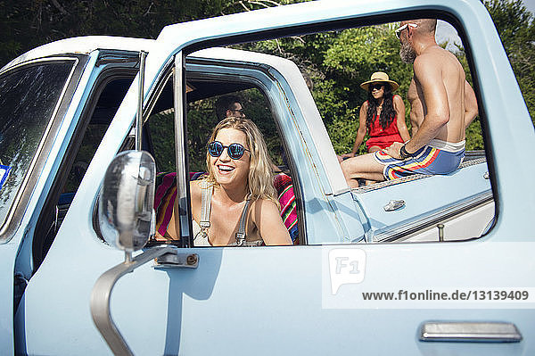 Glückliche Frau mit Sonnenbrille sitzt im Pick-up