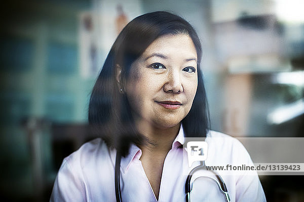 Portrait of confident female doctor seen through window