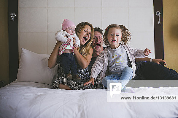 Happy parents with daughters on bed at home