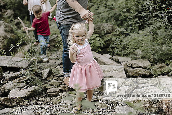 Niedriger Abschnitt von Eltern  die mit Kindern auf Felsen im Wald laufen