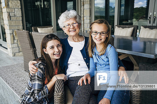 Porträt einer Großmutter mit Enkelinnen auf der Veranda sitzend