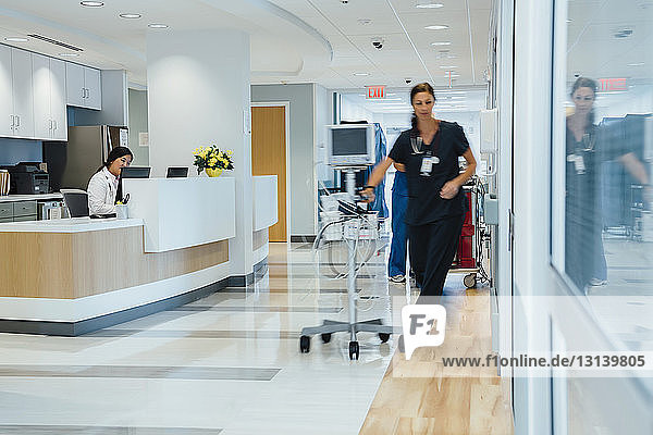 Ärztin  die an der Rezeption arbeitet  während eine Krankenschwester Überwachungsgeräte im Krankenhaus entgegennimmt