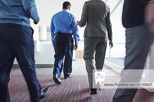 Rear view of business people walking in corridor at office