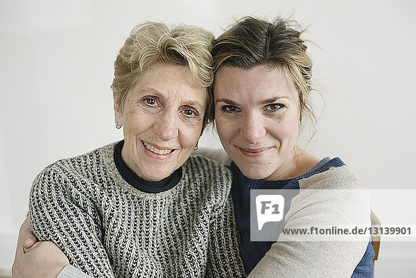 Close-up portrait of mother and daughter against white wall