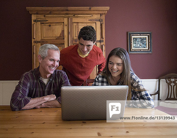 Glückliche Familie mit Laptop-Computer am Tisch zu Hause