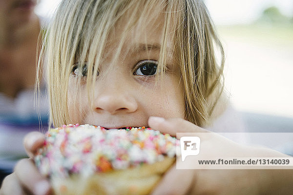Porträt eines süßen Mädchens  das im Freien einen Donut isst