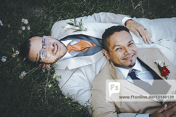 Porträt eines glücklichen homosexuellen Paares auf einem Grasfeld liegend