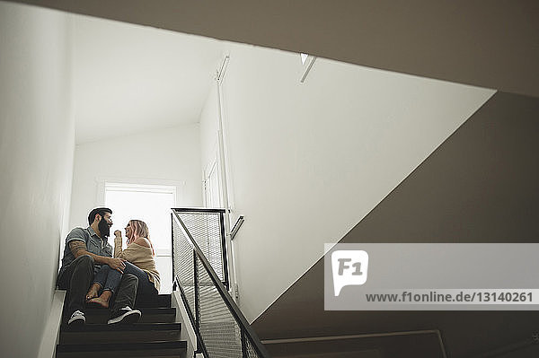 Niedriger Blickwinkel auf ein romantisches Paar  das sich auf einer Treppe zu Hause unterhält