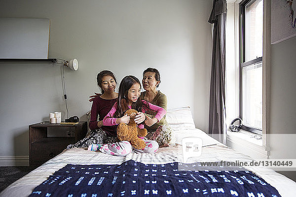 Mother playing with daughters on bed at home