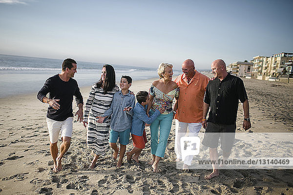 Glückliche Familie geht am Strand gegen den Himmel