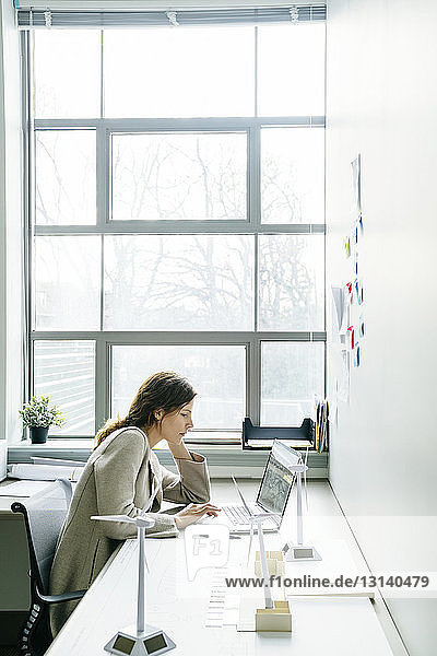Geschäftsfrau benutzt Laptop-Computer  während sie im Büro am Schreibtisch sitzt