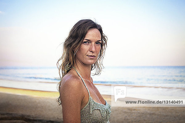 Portrait of beautiful woman at beach against sky