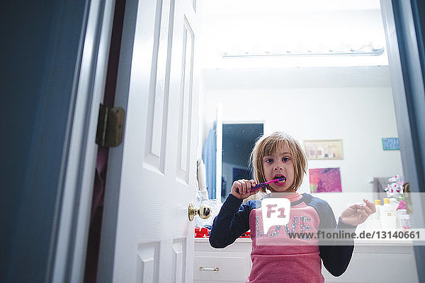 Porträt eines Mädchens beim Zähneputzen im Bad stehend