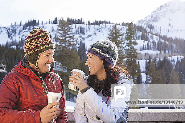 Happy couple having coffee while standing against snowcapped mountains