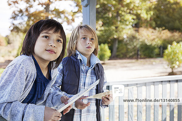 Students holding note pads looking away while standing in gazebo during field trip