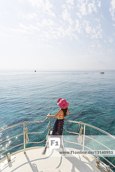 Hochwinkelansicht einer Frau  die bei Sonnenschein auf einem Segelboot gegen den Himmel steht