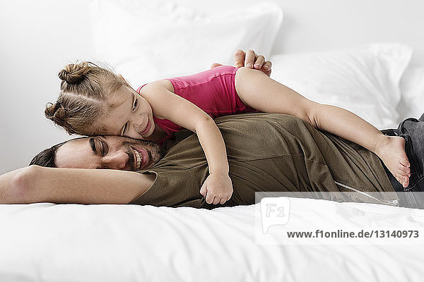 Seitenansicht von Vater und Tochter  die sich zu Hause im Bett entspannen