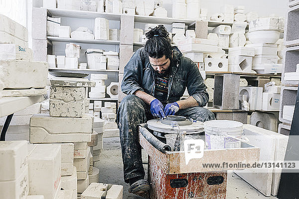 Craftsman using pottery wheel while working in workshop