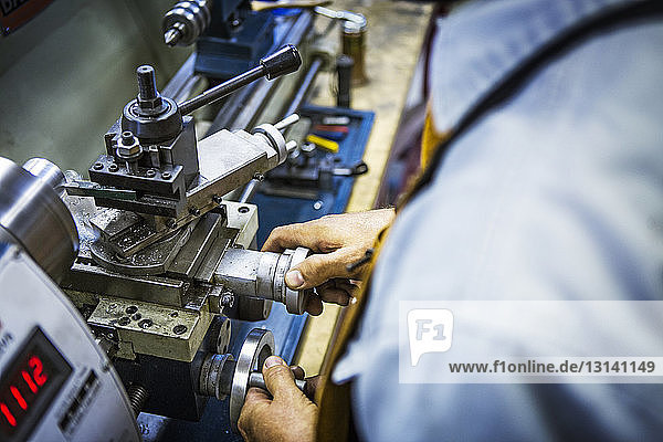 Hochwinkelansicht eines Mechanikers  der in einer Autowerkstatt an Maschinen arbeitet