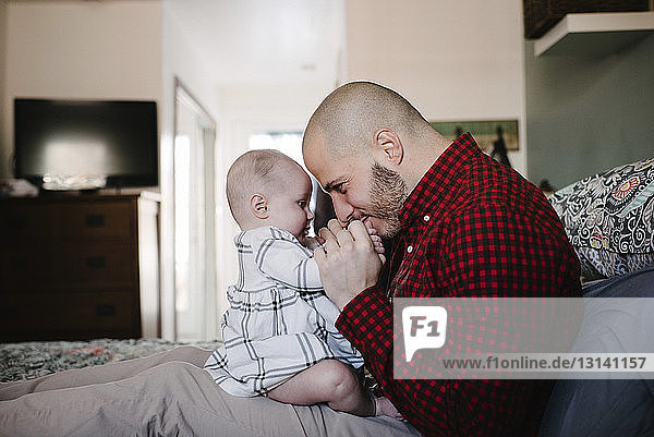 Seitenansicht eines Vaters  der mit seiner Tochter spielt  während er zu Hause im Bett sitzt