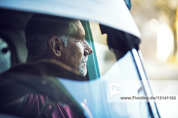 Nachdenklicher Mann sitzt im Auto durch die Windschutzscheibe gesehen