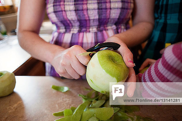 Mitschnitt einer Frau beim Apfelschälen an der Küchentheke