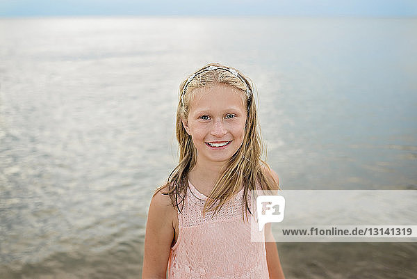 Portrait of smiling girl standing against sea